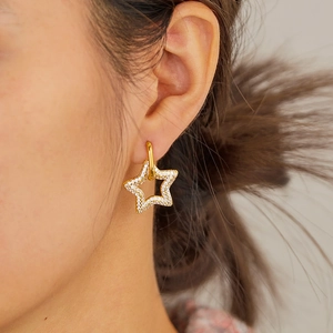 Close-up of golden star drop earrings with sparkling pavé crystals on a female model