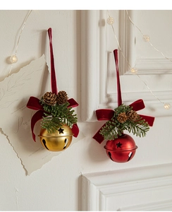 Close-up of Christmas velvet bow bells with pine cones and starry cutout metal texture