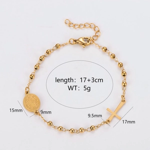 Gold beaded stainless steel bracelet with cross and oval religious medals on gray background