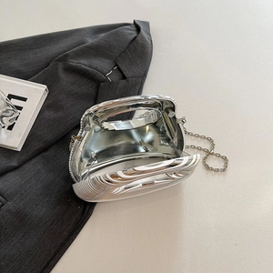 Silver metallic acrylic evening clutch bag with chain strap on grey blazer background
