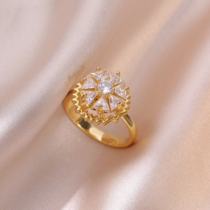 Elegant gold flower ring with round cubic zirconia and sun motif on pink silk background