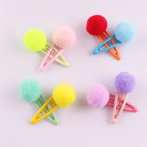 Flat lay of colorful plush ball hair clips for girls in vibrant candy-colored assortment