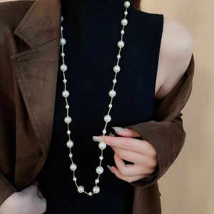 Detail of elegant long faux pearl necklace layered over a black turtleneck sweater