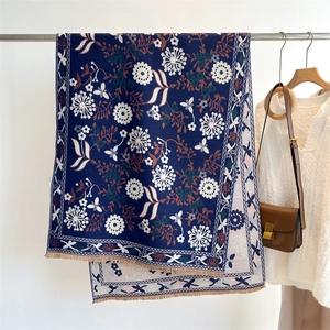 Detailed view of dark blue cashmere-like scarf with floral prints and fringe edges