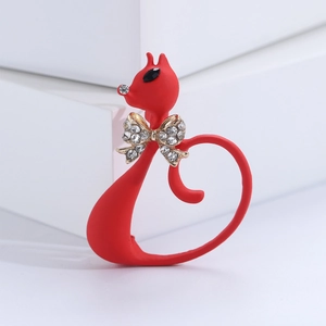Detail of a red enamel cat brooch with a metal rhinestone bow and black gemstone eyes