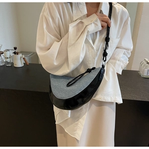 Model showing blue denim crescent shoulder bag with knotted leather strap and metal charms