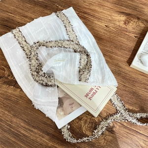 Détail du sac fourre-tout en dentelle florale blanche avec glands tissés bruns