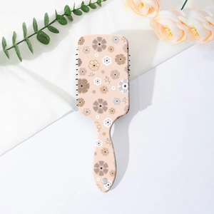 Top view of pink floral air cushion hairbrush with black bristles and decorative flowers