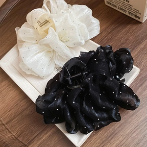 Close-up of large mesh bow hair claws in black and beige with silver polka dot details