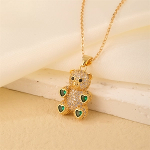 Macro shot of gold bear pendant featuring white zircon pavé and green heart gemstones