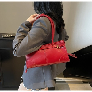 Detail of a red PU leather rectangular shoulder bag with golden buckle on a grey suit