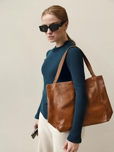 Sac fourre-tout vintage en cuir marron porté par un mannequin pour un look décontracté