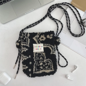Detail of plush black and white jacquard crossbody bag with branded woven label