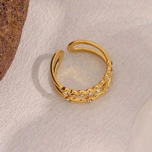Detail of 18K gold-plated double-layer ring with crystals on beige textured surface