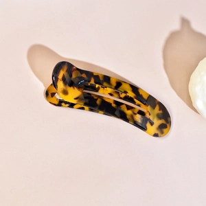 Macro shot of tortoiseshell pattern finish on arc hair claw clip with glossy resin texture