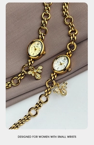 Detail of gold oval watches with charm bracelet strap and crystal bee pendant
