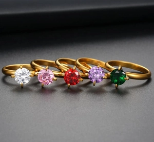 Close-up of five gold-plated titanium steel rings with colorful zircon gemstones in four-prong setting