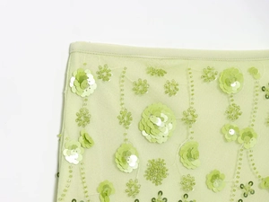 Detail of light green mesh fabric with 3D floral sequins and beadwork embroidery