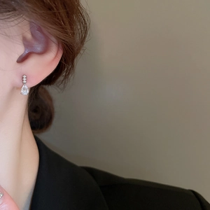 Détail d'une boucle d'oreille goutte d'eau avec zircons brillants portée sur un mannequin