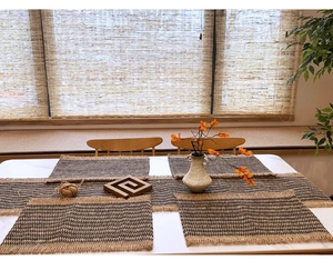Detail of woven table runner and placemat with tassels in a cozy home setting