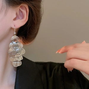 Close-up of a model wearing hollow petal-shaped silver tassel earrings with a metallic finish