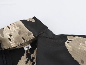 Detail shot of black and beige jacquard fabric neckline with a size S clothing label