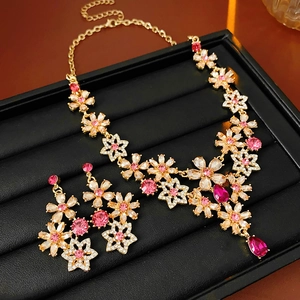 Detail of vintage flower jewelry set with pink crystals on black leather background