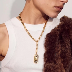 Goldene geometrische Halskette mit Rechteck-Anhänger an einem Model im herbstlichen Look