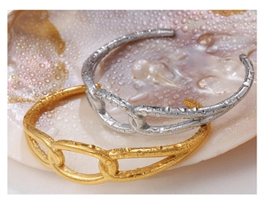 Detailed close-up of interlocking gold and silver metal bangles on a textured shell background