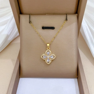 Macro view of gold four-leaf flower pendant with zircon stones on brown jewelry box