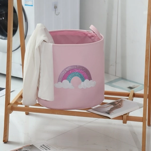 Pink round laundry basket with rainbow pattern on wooden shelf in bright laundry room