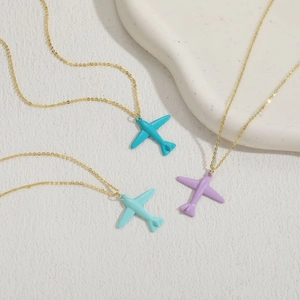 Three gold airplane necklaces with blue and purple paint pendants on a white base