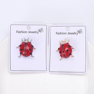 Detail of ladybug brooches with red enamel, crystal accents on gold and silver bases