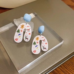 Close-up of Christmas earrings with Santa and Reindeer prints on acrylic display