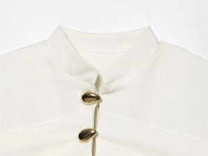 Detail of white blazer collar and unique gold pebble-shaped metal buttons on fabric