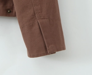 Close-up of brown twill cotton jacket cuff with vintage bronze metal button detail