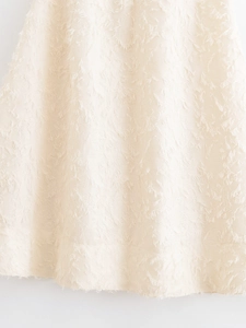 Dettaglio della gonna a frange bianco crema con tessuto jacquard testurizzato a effetto piuma