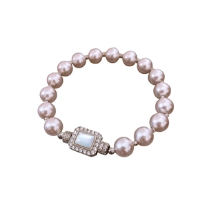 Elegant pink pearl bracelet with a diamond-encrusted square buckle on a white background