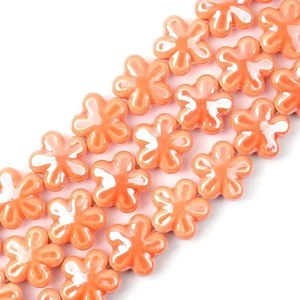 Dettaglio di perline a fiori in ceramica arancione per gioielli fai da te e collane