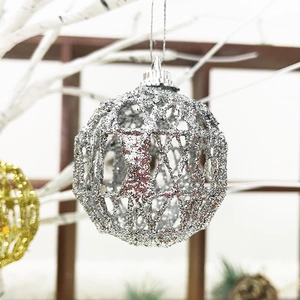 Detail of silver hollow Christmas ball with glitter hanging on a white branch