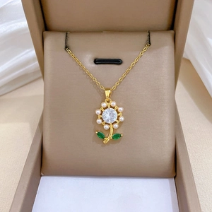 Macro detail of gold flower necklace with pearl petals and green gem leaves on leather