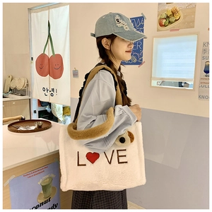 Detail of white plush tote bag with red heart and brown LOVE embroidery on a model