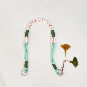 Detalle de una correa ajustable de nailon trenzado para bolso con borlas decorativas