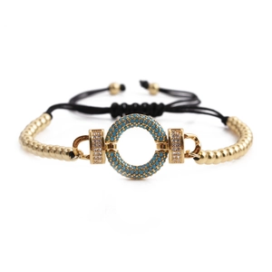 Bohemian adjustable black rope bracelet with blue stone ring and gold beads on white background