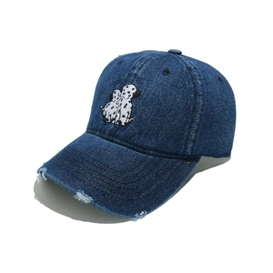 Detail of distressed brim and dalmatian embroidery on dark blue denim baseball cap