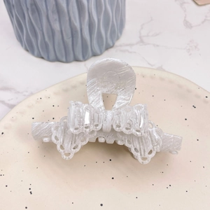 Detail of a white marble texture acetate hair claw clip on a ceramic jewelry tray