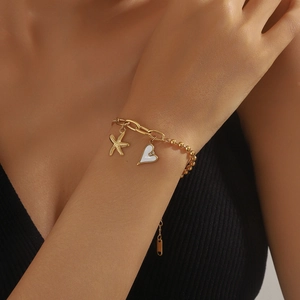 Bracelet doré en acier inoxydable avec pendentifs étoile et cœur sur le poignet