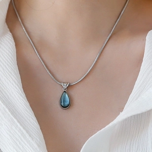 French vintage silver snake chain necklace with blue teardrop pendant on a model