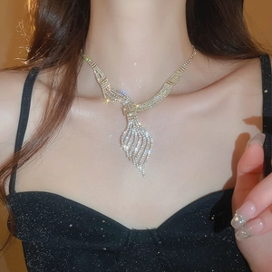 Close-up of golden leaf-shaped rhinestone necklace on model with layered chain detail