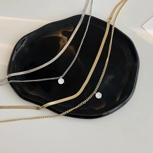 Macro detail of gold and silver snake chains with sparkling round zircon pendants